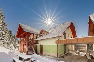 a house in the snow with the sun in the sky at Apartma Valsar Rogla in Zreče