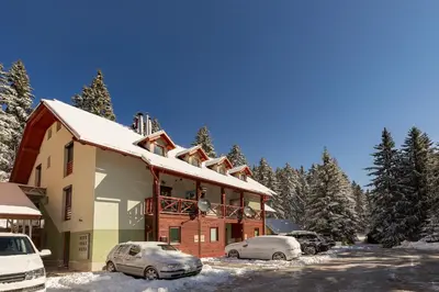 a building with cars parked in the snow at Apartma Valsar Rogla in Zreče