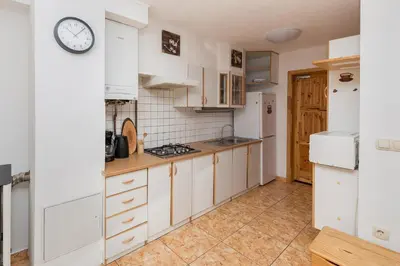 a kitchen with white cabinets and a clock on the wall at Apartma Valsar Rogla in Zreče