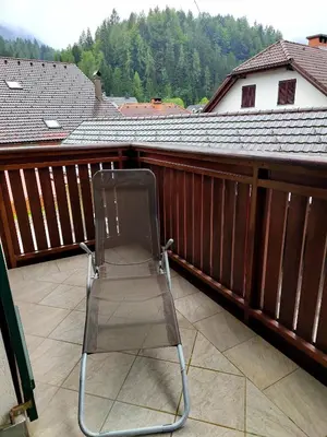 a folding chair sitting on a balcony at Apartma Antico in Kranjska Gora