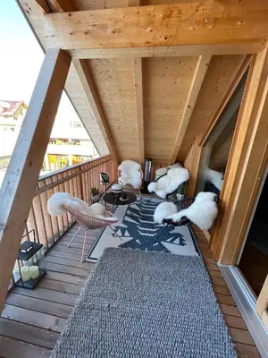 a wooden balcony with white chairs and a table at Sunny Retreat Apartment in Kranjska Gora