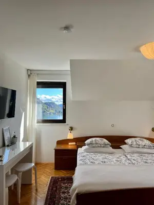 a bedroom with two beds and a desk and a window at Lakeview Guesthouse & Chalet Bled in Bled