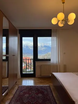 a bedroom with a large window with a view of mountains at Lakeview Guesthouse & Chalet Bled in Bled