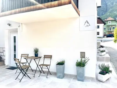 a patio with chairs and a table on a white wall at Apartma Toni Bovec in Bovec