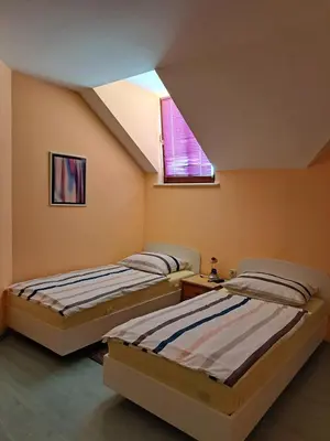 two beds in a room with a window at Rooms Čehovin in Postojna