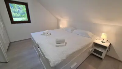 a bedroom with a white bed with a chair on it at Radovna Mountain Valley Cottage in Zgornje Gorje