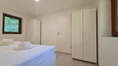 a white bedroom with a bed and a closet at Radovna Mountain Valley Cottage in Zgornje Gorje