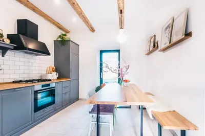 a kitchen with blue cabinets and a wooden table at BELAKAPA Authentic house with garden and free parking in Ilirska Bistrica