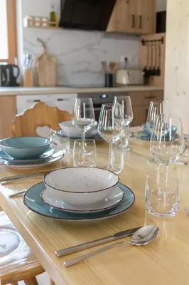 a wooden table with plates and wine glasses on it at Captain's Lodge in Bohinj