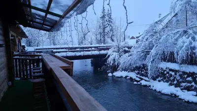 a bridge over a river with snow covered trees at Captain's Lodge in Bohinj