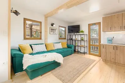 a living room with a green couch and a kitchen at Captain's Lodge in Bohinj