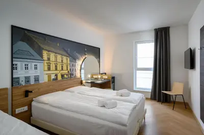 a bedroom with a large bed with a painting on the wall at B&B Hotel Maribor in Maribor