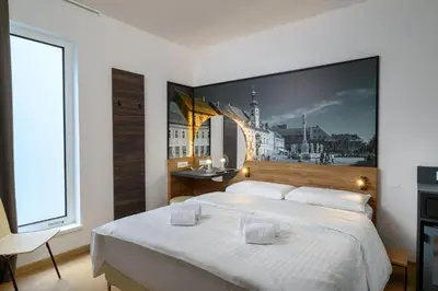 a bedroom with a large white bed with a picture on the wall at B&B Hotel Maribor in Maribor