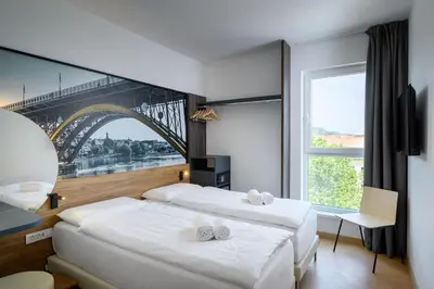 two beds in a room with a view of a bridge at B&B Hotel Maribor in Maribor