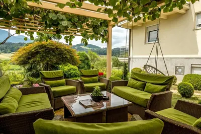 a patio with green furniture and a table and chairs at Relax & Beautiful View in Slovenj Gradec