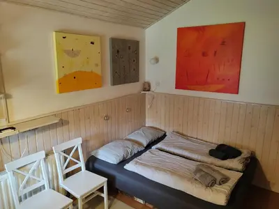 a room with a bed with two chairs and paintings at Cottage Barbara with Sauna in Škofja Loka