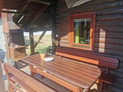 a wooden bench sitting on the porch of a log cabin at Cottage Barbara with Sauna in Škofja Loka