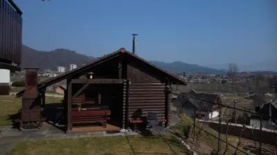 a small wooden cabin with a bench in a city at Cottage Barbara with Sauna in Škofja Loka