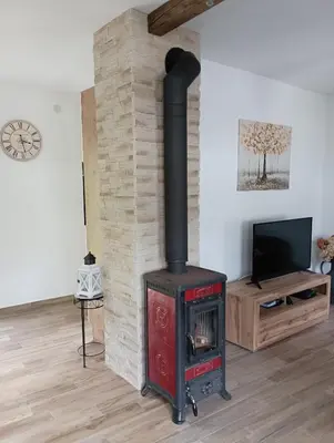 a wood stove in a living room with a tv at Apartma Hči planin in Bovec