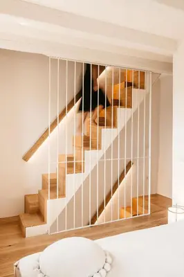 a staircase in a bedroom with white walls and wood floors at Grad Štanjel House in Štanjel