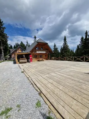 a large wooden building with a wooden deck at Apartma Kadulja Golte in Mozirje