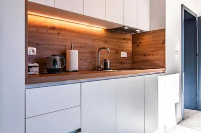 a kitchen with white cabinets and wooden walls at Apartma Kadulja Golte in Mozirje
