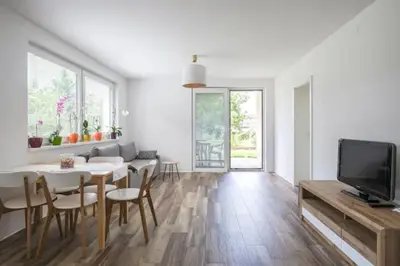 a white living room with a table and a tv at Central Garden House (family friendly!) in Postojna