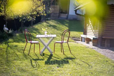 two chairs and a table in a yard with a table at Hiška pod Rudnico 1 in Podčetrtek