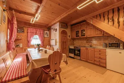 a kitchen with wooden cabinets and a table in a room at Hiška pod Rudnico 1 in Podčetrtek