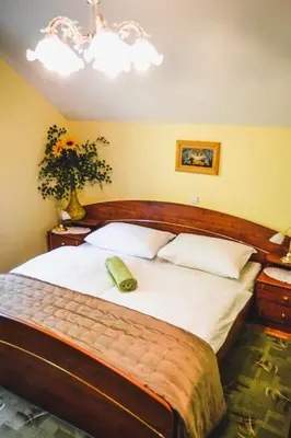 a bedroom with a large bed with a wooden headboard at Apartmaji Krebs in Mežica