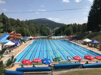 a large swimming pool with red and blue umbrellas at Apartmaji Krebs in Mežica