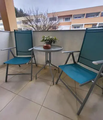 two chairs and a table with a potted plant on a balcony at Apartma Knap Velenje in Velenje
