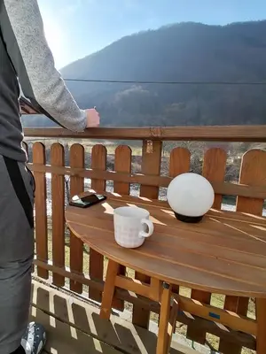 a person standing on a balcony with a table with a coffee cup at počitniška hiška MEDVEJKE in Slappe dʼIdria