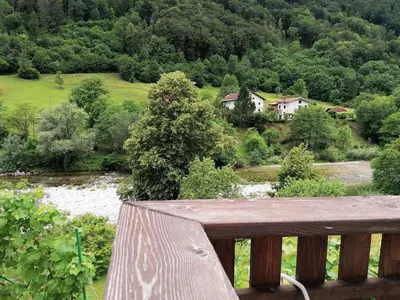 a balcony with a view of a river and a house at počitniška hiška MEDVEJKE in Slappe dʼIdria