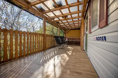 a screened porch with a pergola and chairs on it at Hiška pod Rudnico 2 in Podčetrtek