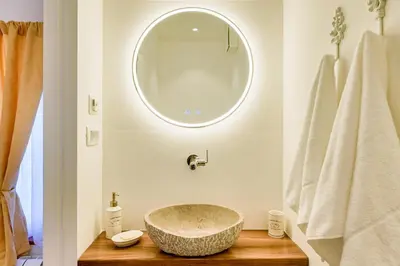 a bathroom with a large stone sink and a mirror at Karst house Žan Pliskovica with private pool in Dutovlje