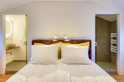 a bedroom with a white bed with yellow and white pillows at Karst house Žan Pliskovica with private pool in Dutovlje