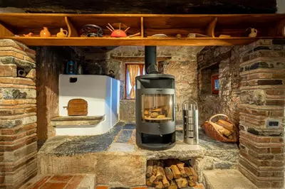 a stove in a stone kitchen with a fireplace at Karst house Žan Pliskovica with private pool in Dutovlje