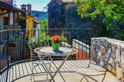 a table with a vase of flowers on a balcony at Karst house Žan Pliskovica with private pool in Dutovlje