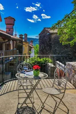 a patio with a table and chairs on a balcony at Karst house Žan Pliskovica with private pool in Dutovlje