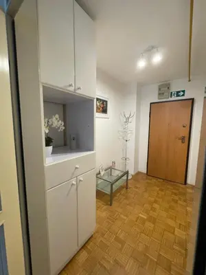 a kitchen with white cabinets and a wooden floor at Apartment Green - Grey in Ljubljana
