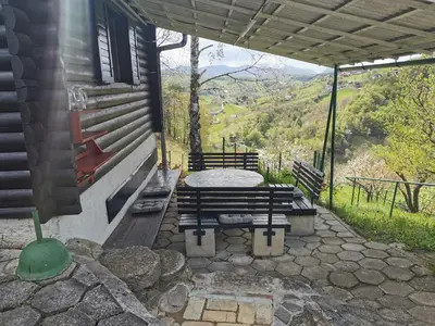 a patio with a bench and a table with a view at KOZJANSKA KOČA in Podčetrtek