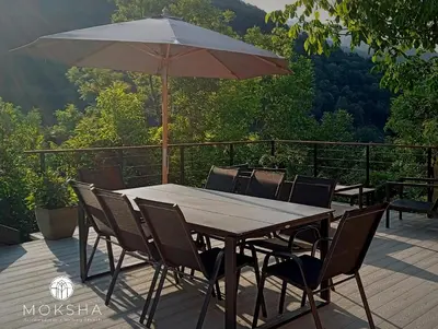 a wooden table with chairs and an umbrella on a deck at Moksha Slovenia in Tolmin