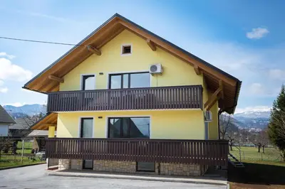 a yellow house with a wooden roof at Apartma Lida 2 in Bled
