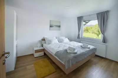 a white bedroom with a large bed and a window at Apartma Lida 1- mirna lokacija, brezplačno parkirišče, 10 minut hoje do jezera in gradu in Bled