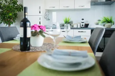 a dining room table with a bottle of wine and glasses at Apartma Lida 1- mirna lokacija, brezplačno parkirišče, 10 minut hoje do jezera in gradu in Bled