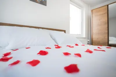 a white bed with red roses on it at Apartma Lida 1- mirna lokacija, brezplačno parkirišče, 10 minut hoje do jezera in gradu in Bled