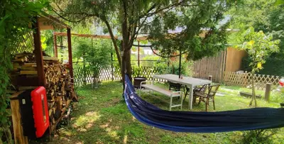 a blue hammock in a yard with a table and a tree at Retro in Tolmin