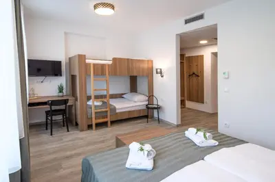 a small room with a bed and a desk and a bunk bed at B&B Pod vrbo in Ljubljana