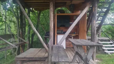 a wooden cabin with a bench in the woods at Treehouse Toplak in Ruše